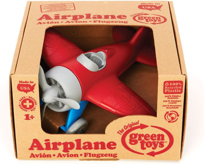 Red toy airplane with grey propeller and blue wheels in a cardboard box labeled 100% recycled plastic.