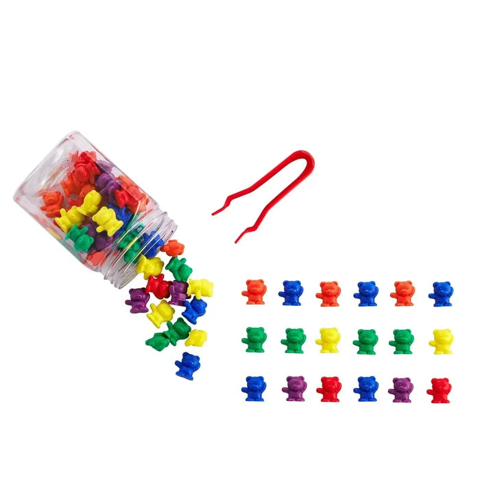 Colorful plastic bear counters spilling from a clear jar next to red tweezers and organized rows of small bears.
