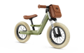 Sage green balance bike with cream tires, brown leather-look saddle, grips, and a matching front storage bag.