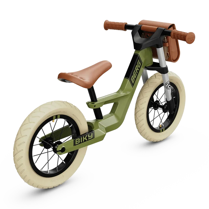 Olive green retro balance bike with cream tires, tan seat, and matching handlebar bag.