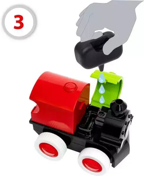 Hand using a dropper to fill a red and black toy train with water through an open green hatch.