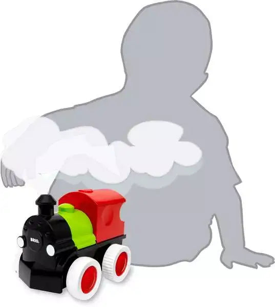 Toy steam engine with red cab, green boiler, and black front against a child silhouette and white steam clouds.