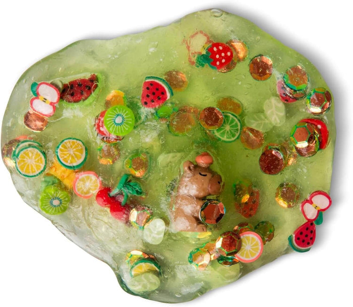 Translucent green sensory putty filled with tiny fruit charms, gold sequins, and a small brown capybara figure.
