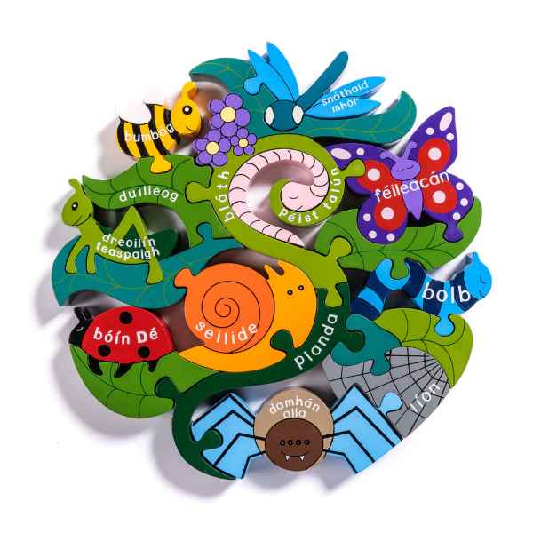 Circular wooden puzzle of colorful garden creatures with Irish names on green leaf and insect-shaped pieces.