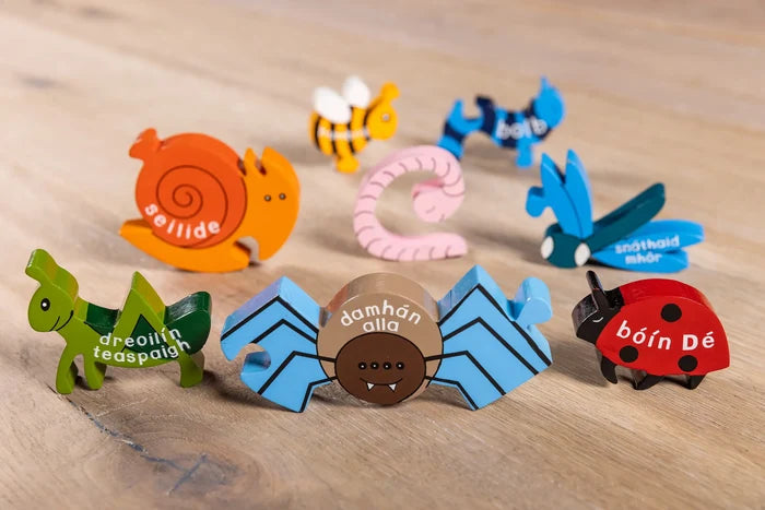 Colorful wooden insect puzzle pieces with Irish names, including a blue spider, red ladybug, and orange snail.