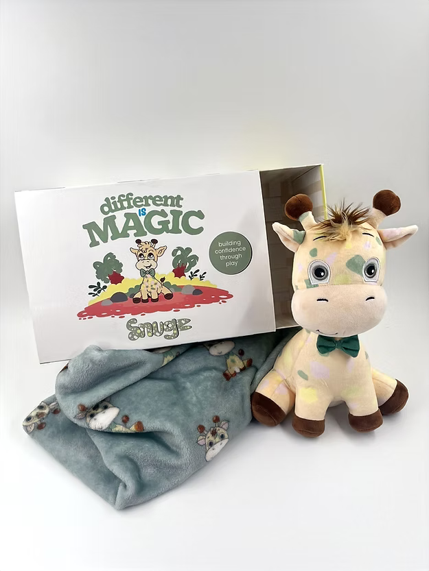White box with a colorful spotted giraffe plush wearing a green bowtie and a matching teal patterned fleece blanket.