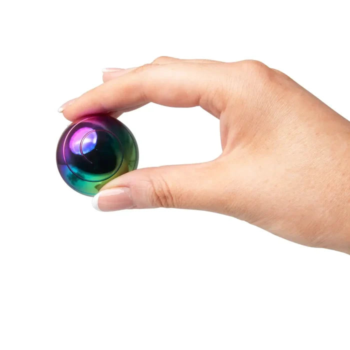 Hand holding a small, metallic, iridescent rainbow sphere between the thumb and forefinger.