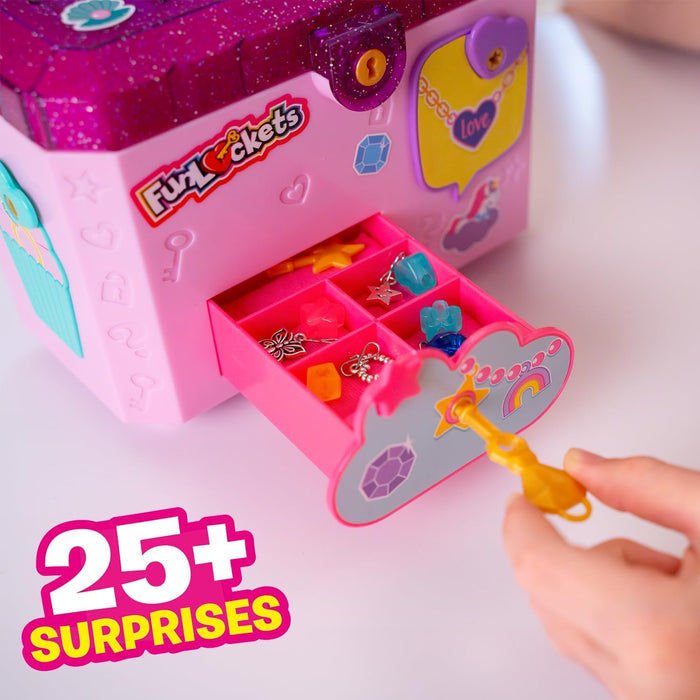 A pink glittery toy jewelry box with an open drawer filled with charms and a yellow key being used to unlock it.
