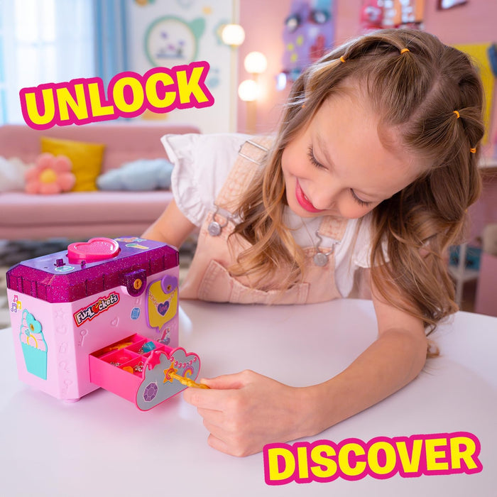 Girl unlocking a pink and purple glittery toy jewelry box with a gold key and pull-out drawer.