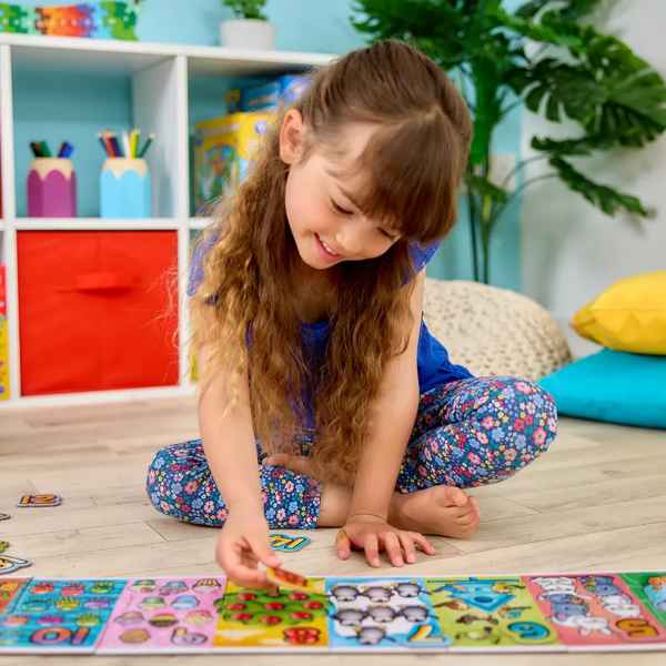 Young girl assembling a long, colorful number jigsaw puzzle on the floor featuring vibrant animal illustrations.