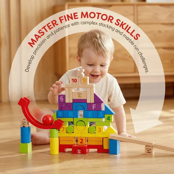 Toddler playing with colorful wooden blocks stacked in a tower featuring numbers, letters, and a red marble run.