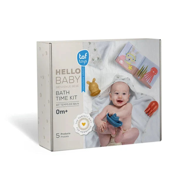 White box for Taf Toys bath kit featuring a baby in a hooded towel, blue toy boat, red octopus, and soft cloth book.