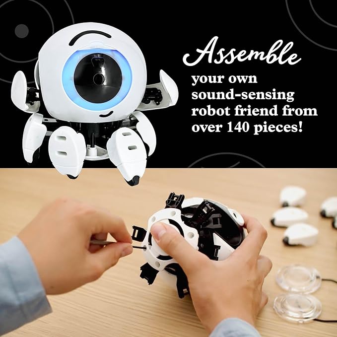 White spherical robot with a glowing blue eye above hands assembling internal parts with a screwdriver.