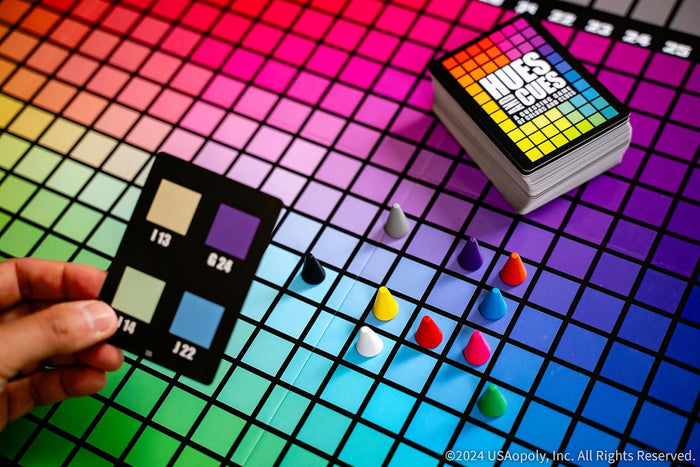 Vibrant rainbow grid game board with colored cone markers and a hand holding a card with color swatches.