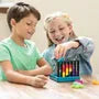 Two children drop colorful, interconnected bead pieces into a vertical teal puzzle frame on a wooden table.