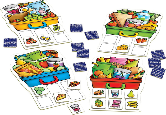 Four colourful lunch box game boards with various illustrated food tiles and face-down blue matching cards.