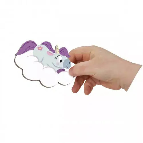Hand holding a magnet of a white unicorn with a purple mane and gold horn resting on a fluffy white cloud.