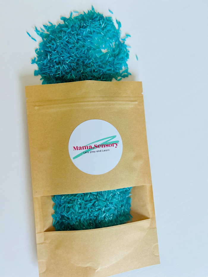 Bright teal sensory rice in a brown kraft bag with a clear window and logo, with rice spilled at the top.