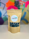 Teal, silver, and black chickpeas in a kraft paper bag with a clear window and circular Mama Sensory label.