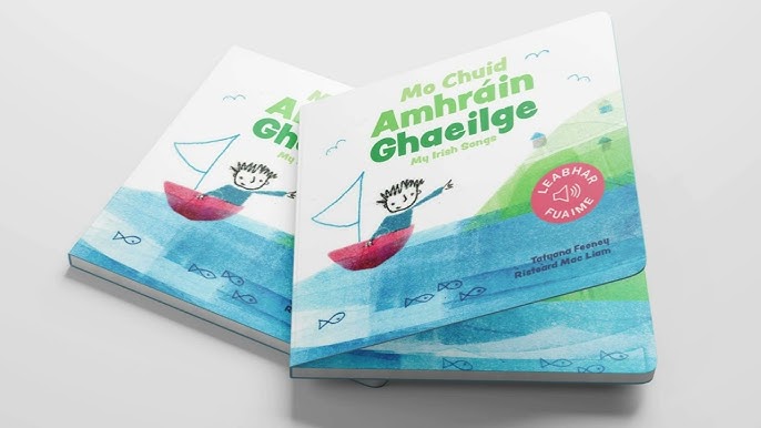 Two white board books featuring a boy in a red sailboat on blue water, green Irish text, and a pink sound icon.