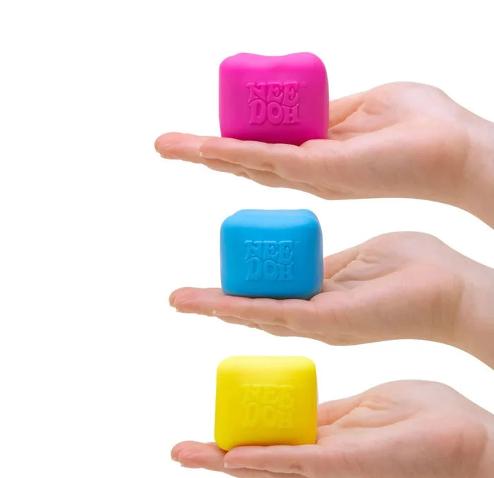 Pink, blue, and yellow squishy square cubes with embossed logos, each resting on an open hand.