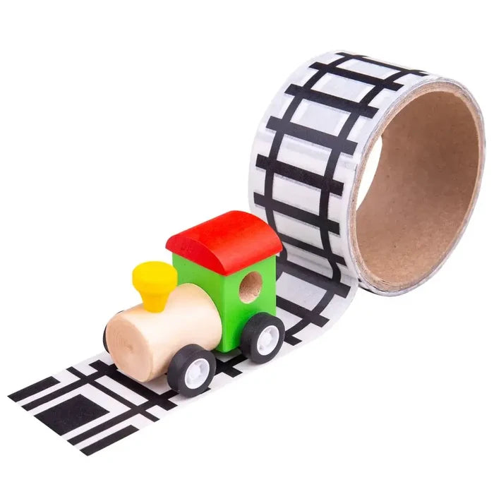 White tape roll with black train track print and a small wooden toy train sitting on an unrolled section.