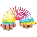 Hands holding a vibrant, multicolored plastic spring toy arched into a rainbow shape.