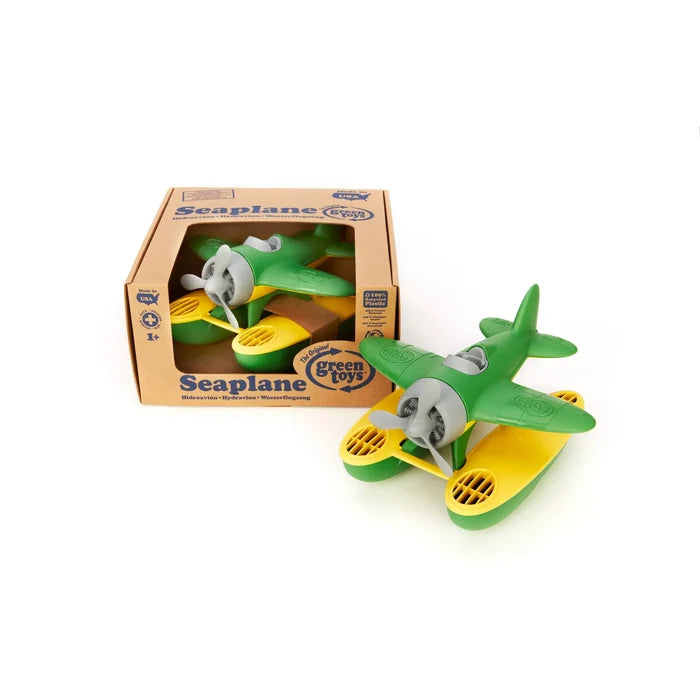 Green and yellow toy seaplane with gray propeller, shown next to its open cardboard packaging on a white background.