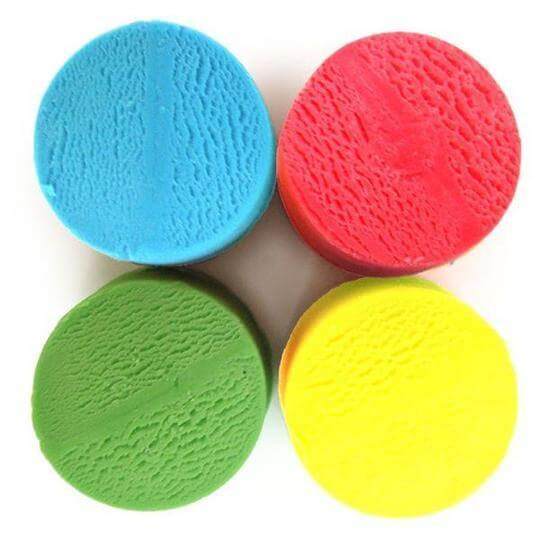 Four textured circular mounds of bright blue, red, green, and yellow play dough arranged in a square.