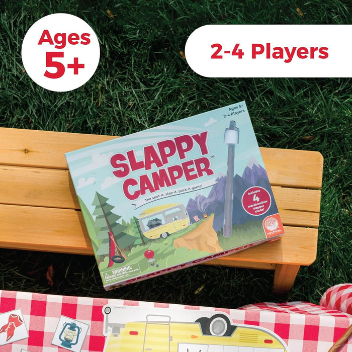 Slappy Camper board game box on a wooden bench featuring camping art, a yellow camper, and marshmallow slapper sticks.