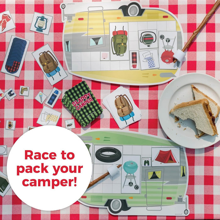 Camping board game with camper-shaped boards, gear cards, and marshmallow sticks on a red and white checkered tablecloth.
