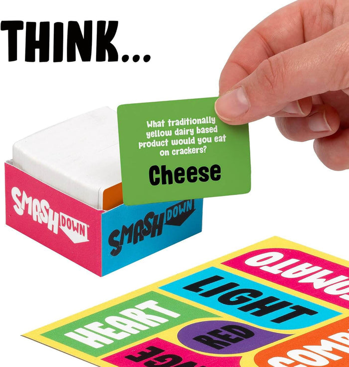 Hand holding a green trivia card over a pink and blue game box and colorful word boards like Heart and Light.