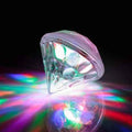 Clear faceted diamond toy projecting vibrant multicolored light patterns onto a dark reflective surface.