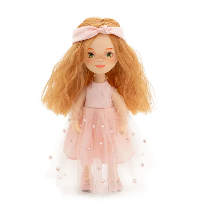 Doll with wavy orange hair, a pink headband, and a light pink dress with a pearl-studded tulle overlay.