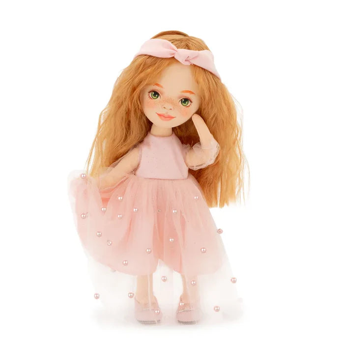 Ginger-haired doll with green eyes and freckles in a pink tulle dress with pearl accents and a knotted headband.