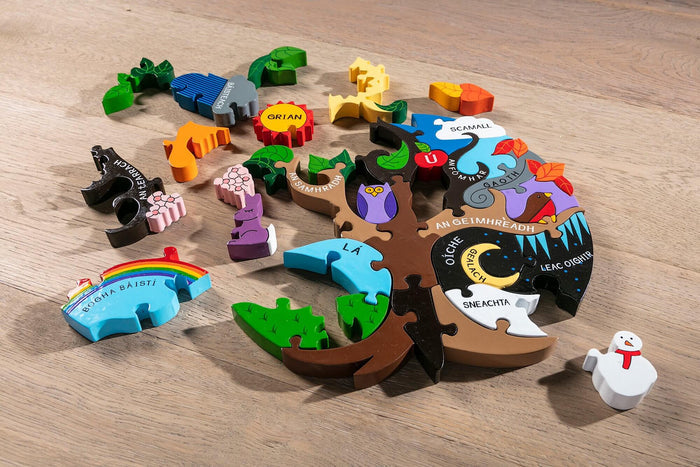 Colorful wooden tree-shaped puzzle with Irish text and seasonal pieces scattered on a light wood surface.