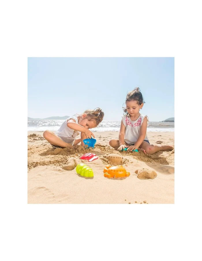 Two young girls play on a beach with colorful star, fish, crab, and caterpillar shaped sand molds.