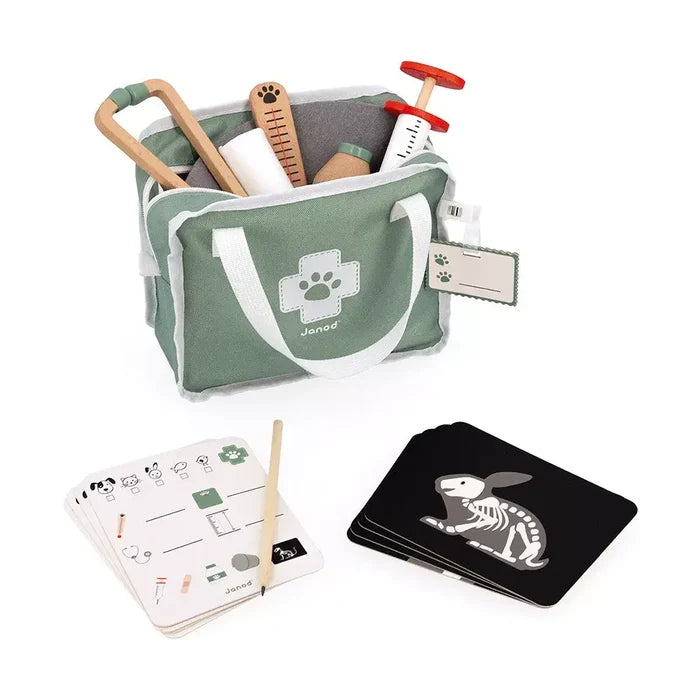 Green toy vet bag with wooden medical tools, health checklists, a pencil, and animal x-ray cards.