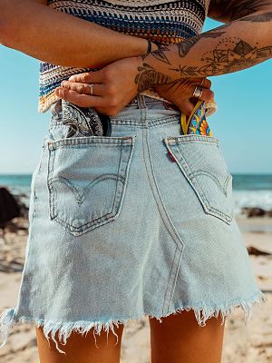 Two colorful, patterned silicone flying discs tucked into the back pockets of a denim skirt, showcasing portability.