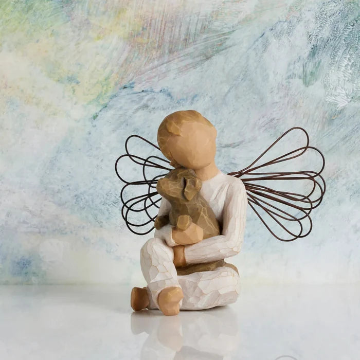 Decorative angel figurine holding a teddy bear against a textured background