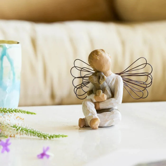 Decorative figurine of an angel holding a dog on a light surface with a blurred background