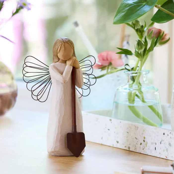 Decorative angel figurine with a shovel in a home setting with plants.