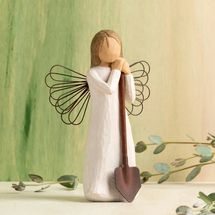 Angel figurine holding a shovel with a green and beige background