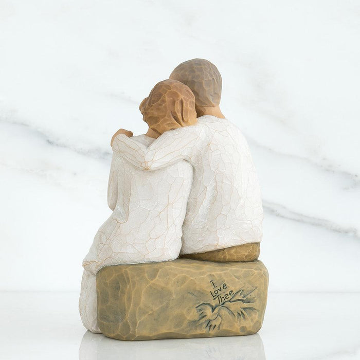 Statue of a couple embracing on a rock with 'I love thee' engraving against a white background