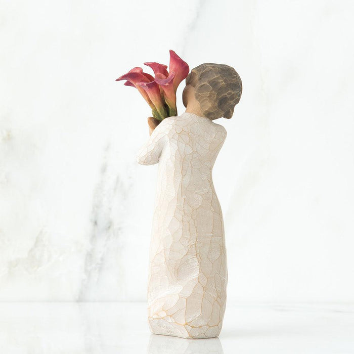 Decorative figurine of a woman holding flowers against a white background