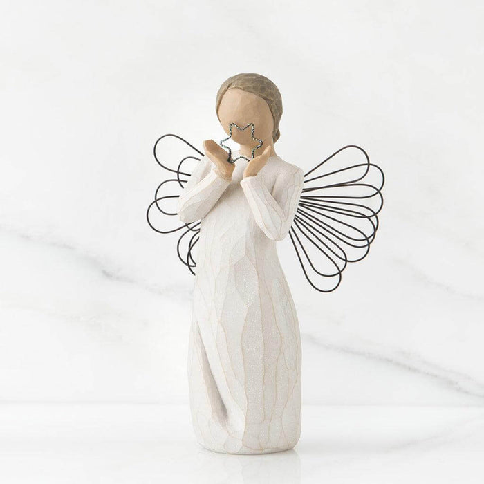 Angel figurine with outstretched wings holding a heart on a white background