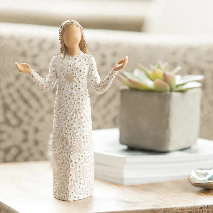 Decorative figurine of a woman in a white dress with lace details on a table.