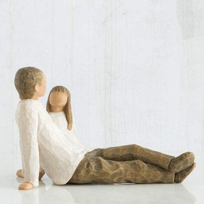 figures of a Father and a daughter  sitting closely on a white surface.