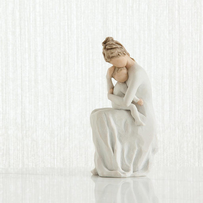 White ceramic figurine of a woman sitting with her child on a white background