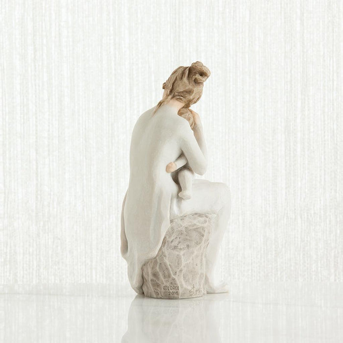Statue of woman sitting with a child in her lap on a textured white surface